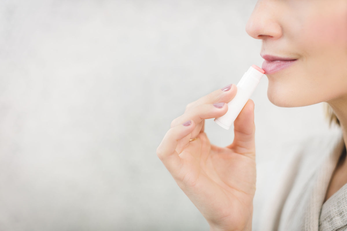 Close-up of a smiling woman applying lip balm