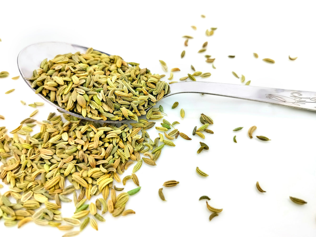 Spoonful of fennel seeds on a white surface